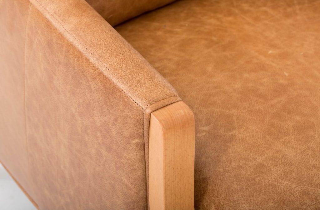 A top-grain brown leather couch with wooden legs