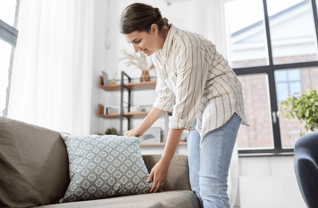 Woman happily adjusting cushions on her sofa.