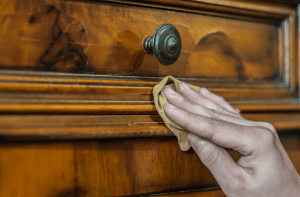 Close up of hand using cloth to clean wooden closet door