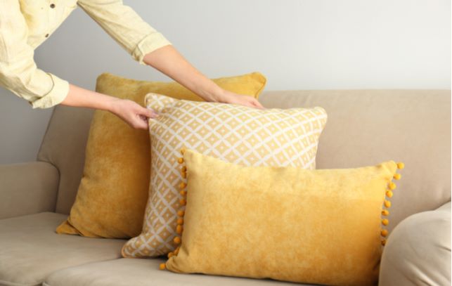 Close up of women hand placing different pillows on sofa