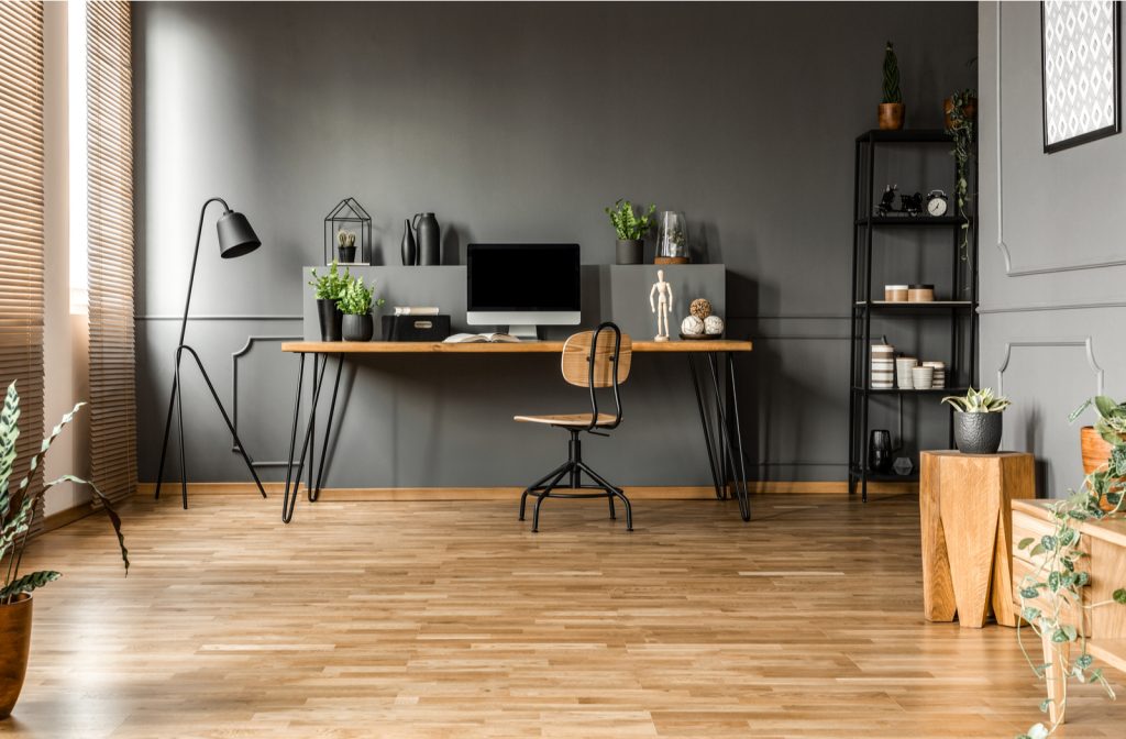 Home office with wooden table with computer monitor and plants with wooden chair