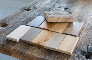 Different types of wood samples for furniture making sitting on a rustic wood table.