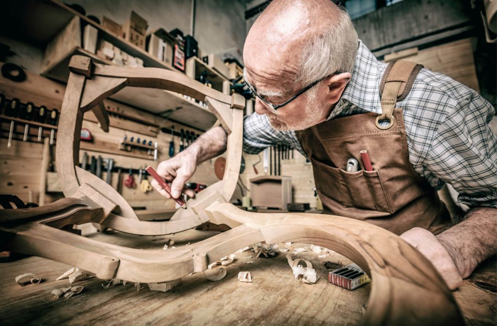 A male wood worker is creating a sample of a custom chair for his client.