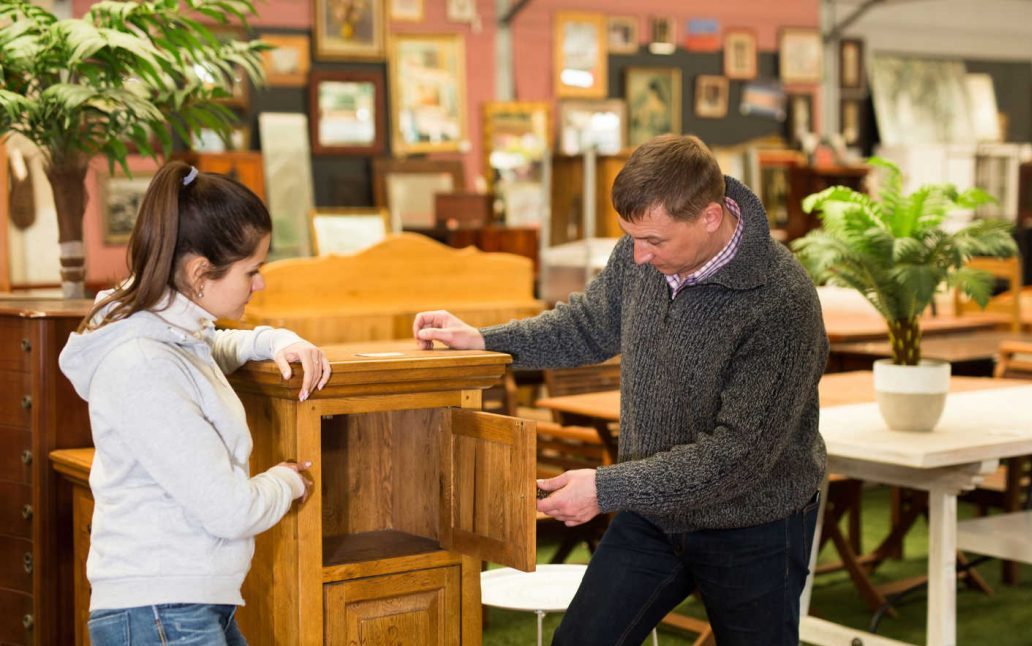 A couple looking at a piece of wood furniture closely to see if it is solid wood.