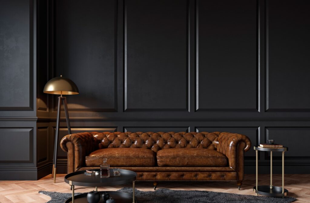 A luxury brown leather sofa against a black wall in an elegant office space.